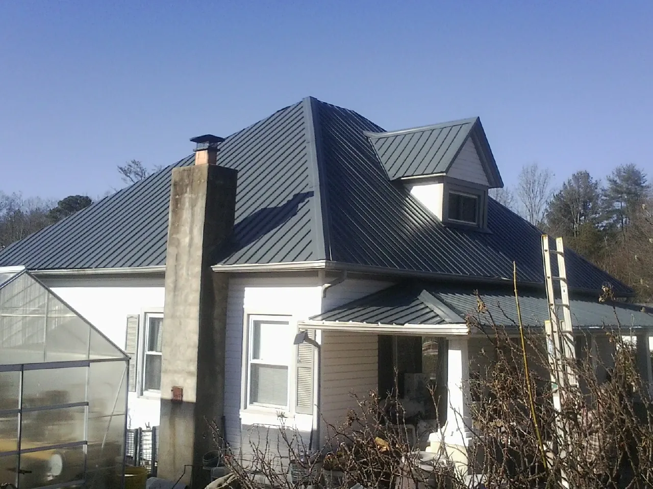 Dark blue standing seam metal roof on a white farmhouse with dormer — Slate & Tile Roof Repair by Roofing Brothers in Beulah