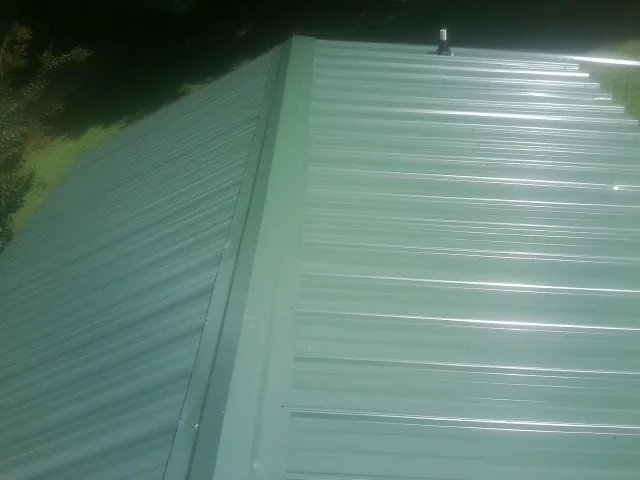 New green metal panels meeting at the ridge of a roof — Flat Roof Repair work by our crew in Beulah