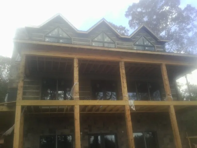 Dormers and porch framing on a large log home under construction — Roof Coating work by our crew in Beulah